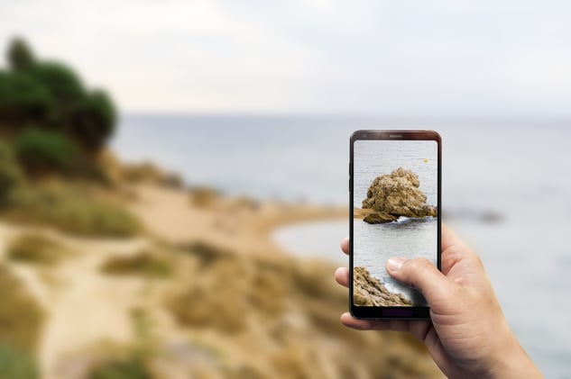 closeup-hand-holding-phone-taking-photo-beach