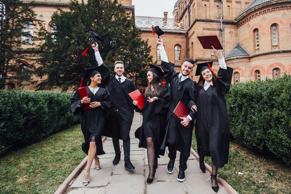 successful-graduates-academic-dresses-are-holding-diplomas-looking-camera-smiling-while-standing-outdoors-lifestyle